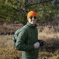 hiker in green jacket wearing blaze orange beanie
